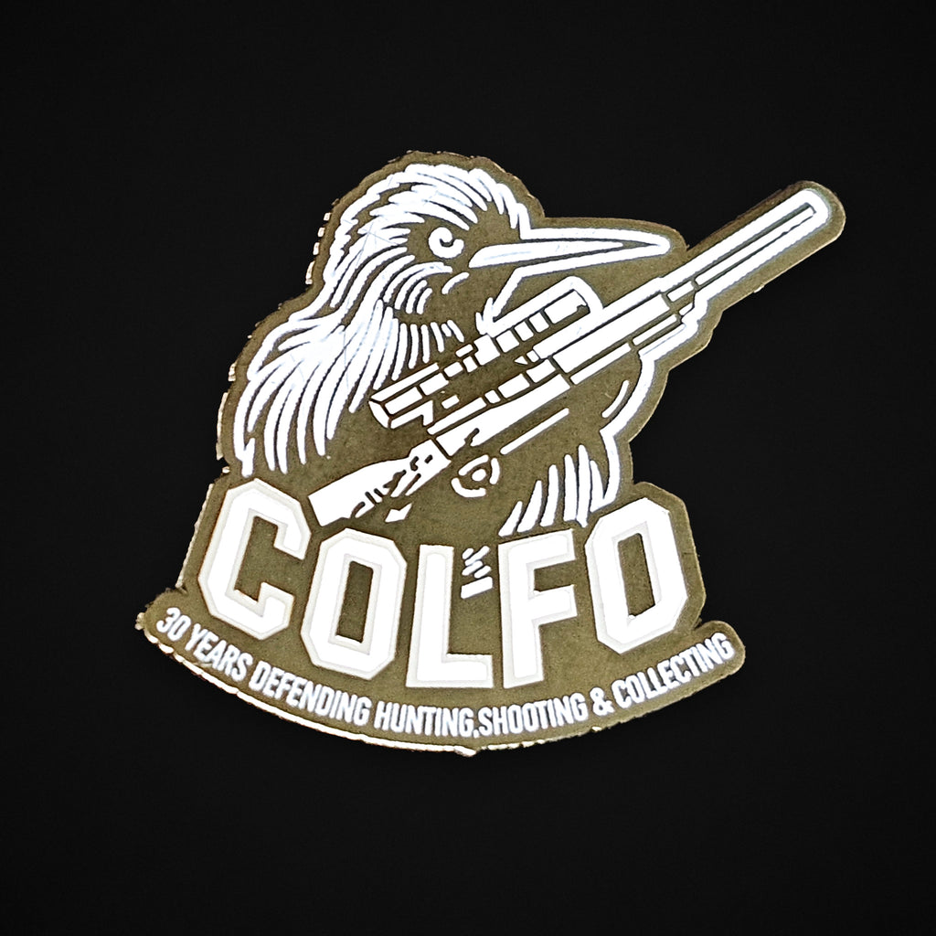 Front of the COLFO 30 year silver anniversary badge, showing a kiwi holding a scoped rifle above COLFO and the words 30 Years Defending Hunting, Shooting & Collecting
